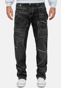 Pantaloni in denim neri con molteplici tasche, cuciture bianche a contrasto e dettagli distintivi come rivetti e accenti ricamati.