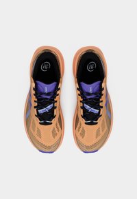 Αθλητικά παπούτσια ελαφριάς κατασκευής με διχτυωτό επάνω μέρος σε ροδακινί χρώμα με μαύρες και μοβ λεπτομέρειες. Μαύρα επίπεδα κορδόνια και μαλακός σχεδιασμός στον γιακά.