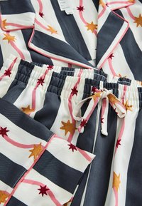 Gestreiftes Schlafanzug-Set in Marineblau, Weiß und Rosa, mit Sternmustern und einem Kordelzugbund aus weichem Material.