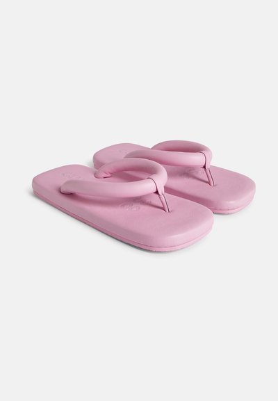 Lyserøde flip-flops med en glat mat finish, der har et cirkulært tåpost og polstrede såler. Minimalistisk design med en blød tekstur.