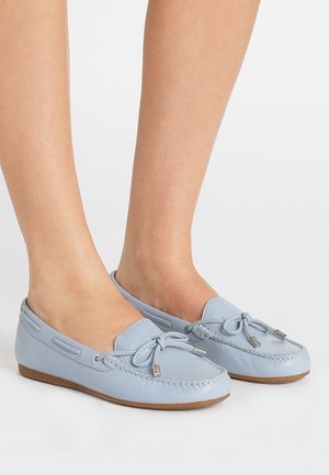 Lichtblauwe leren mocassinschoenen met een strikaccent, platte bruine zool en gestikte details langs de randen.