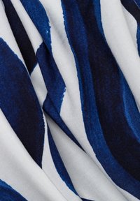 Tessuto con righe ondulate in blu scuro e bianco. Stoffa morbida con una trama liscia, che mostra una combinazione di colori e motivi.