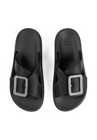 Black sandals featuring a cross-strap design, synthetic materials, textured footbed, and a silver rectangular buckle accent.