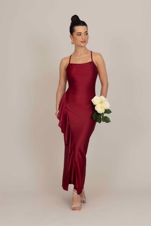Satinburgunderkleid mit figurbetonter Silhouette, Spaghetti-Trägern und einem drapierten Rüschendetail auf der linken Seite; kombiniert mit weißen Rosen.