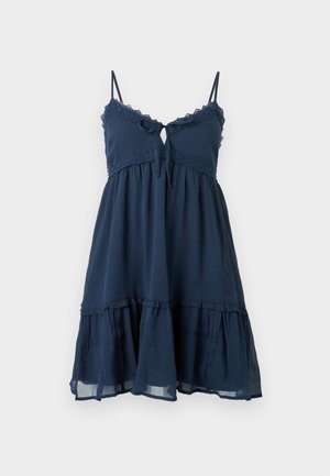 Navy blue sleeveless dress with lace trim, tie at neckline, gathered waist, and tiered ruffle hem.
