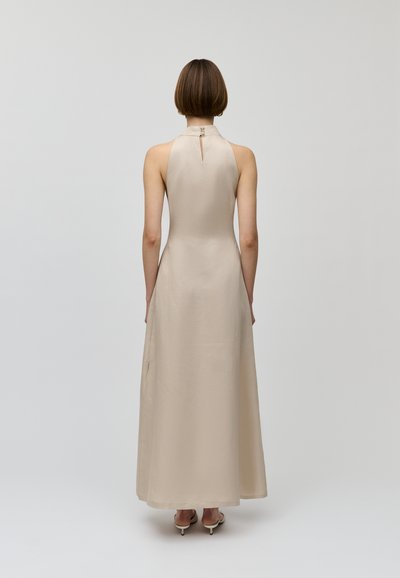 Beige Halsbandkleid mit fließender Silhouette, das ein Rückenschlüssellochdetail und eine glatte Textur aufweist. Lange Länge mit minimalistischem Design.