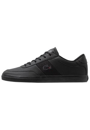 Baskets basses noires à lacets, panneau latéral texturé et petit logo crocodile sur le côté extérieur.