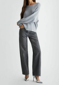 Světle modrý svetr se širokými rukávy, kombinovaný se širokými tmavě šedými džíny s třpytivým efektem a stříbrnými metalickými vysokými podpatky.