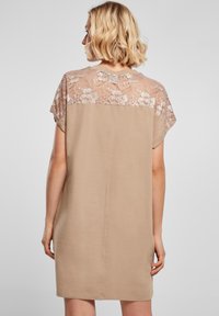 Beežikas kleit lühikeste varrukatega, millel on pitsist ülaosas seljaosa detail. Sile kangas, lõdvestunud lõige ja põlvepikkune lõige.