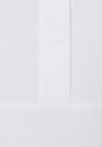 Tessuto bianco con una superficie liscia, caratterizzato da una cucitura verticale e una finitura pulita. Design semplice senza motivi o decorazioni.