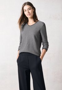 Grårandig långärmad topp med rund halsringning, kombinerad med svarta byxor med elastisk midja, vilket framhäver en avslappnad passform och mjuk textur.