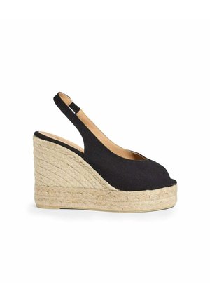 Zwarte stoffen sleehak sandalen met hielbandje, open teen en gevlochten jute plateauhak op witte achtergrond.