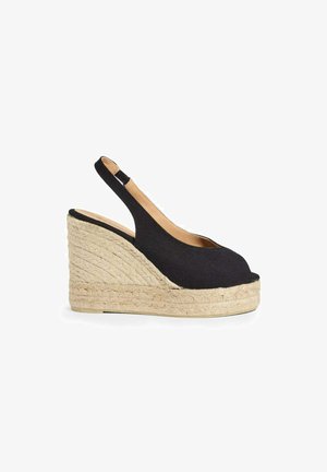 Zwarte stoffen sleehak sandalen met hielbandje, open teen en gevlochten jute plateauhak op witte achtergrond.