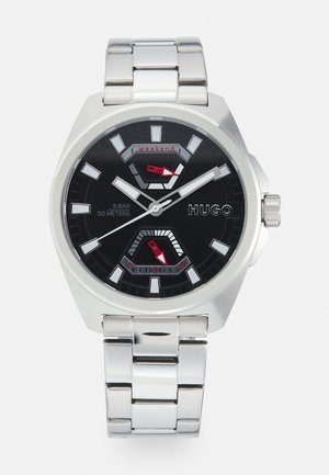 Reloj de acero inoxidable plateado con esfera negra, acentos rojos y marcadores de hora distintivos. Presenta sub-esferas dobles para una funcionalidad adicional.