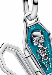 Ciondolo a forma di bara argentata con sfondo blu glitterato, raffigurante un piccolo scheletro con occhi di gemma, appeso a una catena.