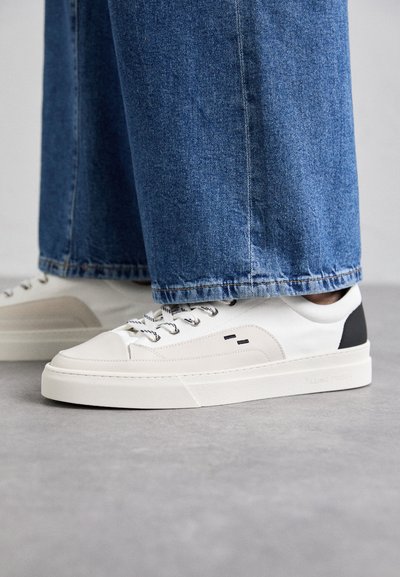 Witte en zwarte sneakers met een glad leren bovenwerk, textuuraccenten en een chunky witte zool. Heeft een klassiek vetersluiting ontwerp.