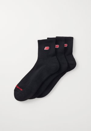 Calcetines de crew de algodón negros en un pack de tres. Puños acanalados, con el logo rojo de New Balance en cada calcetín y un acento de texto rojo en la punta.