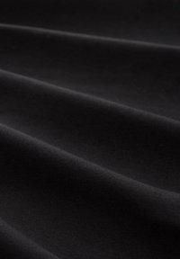 Schwarzer Stoff mit glatter Textur, der subtile Rippungen und Falten aufweist und eine tiefe, einheitliche Farbe ohne Muster oder Akzente präsentiert.