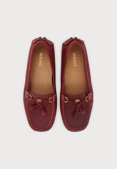 Paire de mocassins en daim rouge avec pampilles, coutures blanches et garnitures dorées, marqués Versace à l'intérieur.