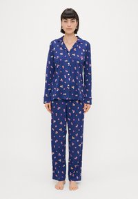 Conjunto de pijama azul-marinho em tecido macio, com estampa floral. Top de manga longa com fecho de botão e calças coordenadas. Sem padrão nas mangas.