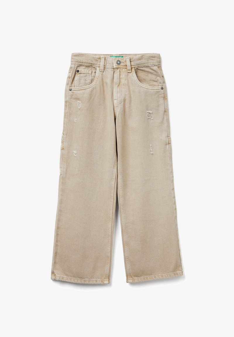 Béžové široké džíny s lehkým opotřebením, pěti kapsami, zapínáním na knoflík a poutky na opasek, položeny na bílé pozadí.