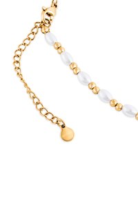 Złoty naszyjnik z łańcuszkiem, ozdobiony białymi owalnymi koralikami i złotymi kulistymi akcentami, z zapięciem typu lobster i okrągłą zawieszką.