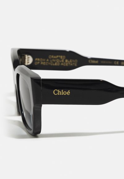 Black sunglasses crafted from a unique blend of recycled acetate. Features bold square frames and gold "Chloé" logo on the arm.