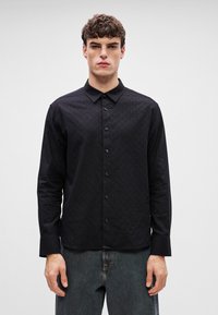 Mustmustel must shirt, mille-soom kui jooned, pikad varrukad ja punktkraed. Ees nööbikinnitus sobivate nööpidega.