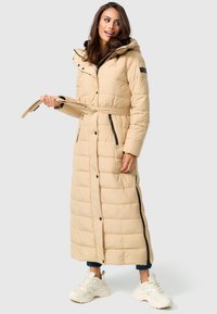 Manteau long beige en duvet avec une taille ceinturée, doté d'une capuche, de boutons-pression et de détails zippés noirs. Texture épaisse matelassée. Coupe décontractée.