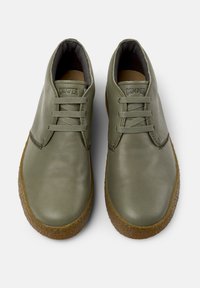 Scarpe in pelle verde oliva con punta rotonda, design con lacci e suola in gomma di colore contrastante. Presentano il logo "Camper" sulla linguetta.