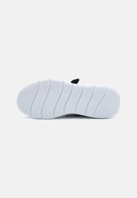 Semelle de chaussure avec une surface en caoutchouc blanc texturé, présentant des rainures horizontales et un accent de logo. Matériel noir au talon.
