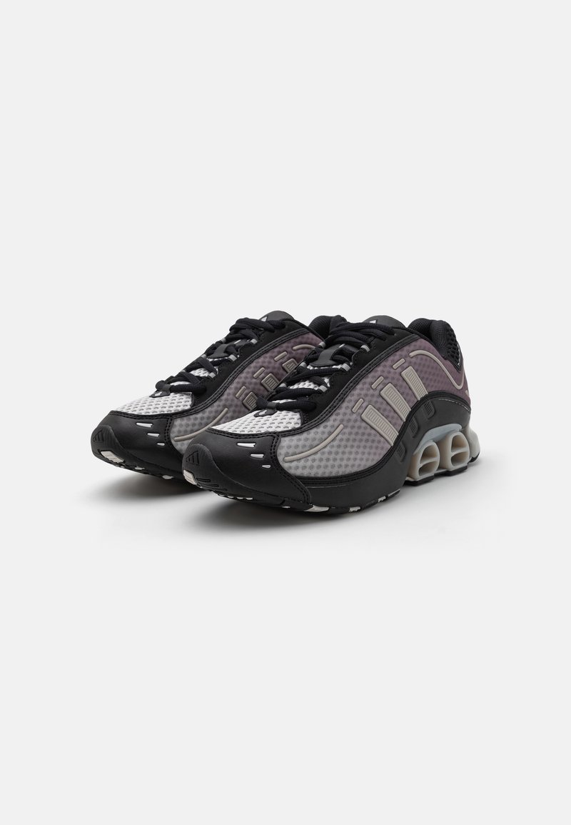 Buty sportowe z siateczkową cholewką w odcieniu szarym, z czarnymi akcentami, lekką, amortyzującą podeszwą oraz wyraźnymi elementami designu.