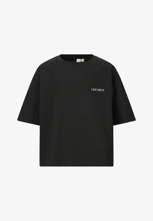 Sort kortærmet t-shirt med hvid tekst, parret med lysegrå, løstsiddende sweatpants og beige sko. En enkel og afslappet påklædning.