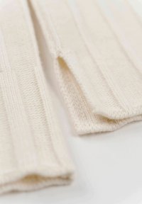 Gestrickte, ungefütterte Baumwollhandschuhe in Creme, mit geripptem Muster und offenen Spitzen für die Finger. Weiches Material mit glatten Kanten.