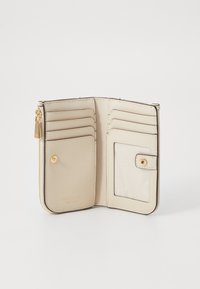 Beige läderplånbok med åtta kortfack, en dragkedjeficka och ett klart ID-fönster. Utrustad med guldfärgad metall och sömnadsdetaljer.