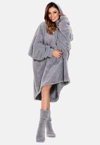 Sudadera con capucha de felpa gris, de corte amplio, con capucha, mangas largas y gran bolsillo frontal. Presenta una textura suave y un dobladillo a la altura de los tobillos.