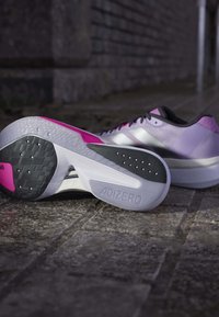 Lekki obuwie do biegania z gradientowym wzorem w odcieniach purpury i różu, teksturowana biała podeszwa z czarnymi akcentami oraz strukturalne sznurowanie.