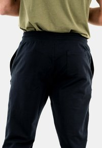 Pantalones jogger azul marino con cinturilla elástica, bolsillos laterales y un único bolsillo trasero. Fabricados en un tejido suave y ligero.