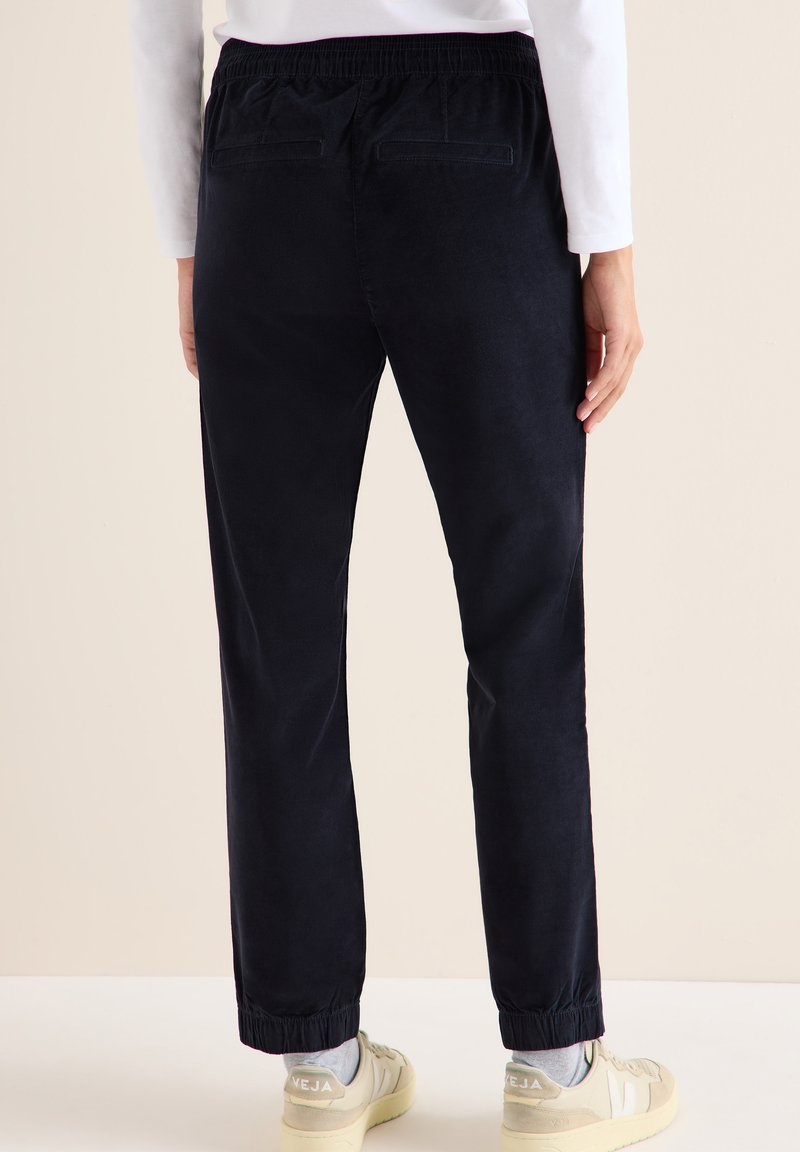 Granatowe spodnie z kordurowej tkaniny w luźnym kroju, z elastycznym pasem, wykończonymi mankietami i dwiema tylnią kieszeniami.