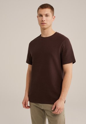 Brun kortærmet t-shirt med en tekstureret overflade, rund halsudskæring og afslappet pasform, parret med lyse bukser.