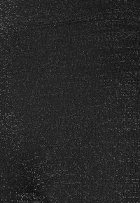 Gros plan sur un tissu noir avec de fins fils de paillettes argentées uniformément espacés, créant une texture subtilement scintillante.