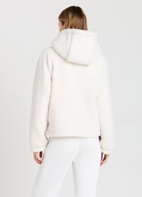 Felpa cropped in morbido pile bianco con un grande cappuccio. Presenta polsini e orlo a costine, e una vestibilità rilassata per il massimo comfort.