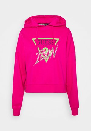 Lys pink Guess hættetrøje med grønt trekantslogo og glitrende "ICON" tekst på forsiden, med snøre i hætten og lange ærmer.