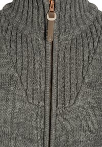 Suéter gris de punto con cuello alto, que presenta una cremallera marrón y una textura acanalada. El diseño incluye patrones de punto verticales.