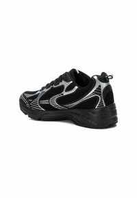 Zapatilla deportiva negra con parte superior de malla, acentos plateados, cuello acolchado y suela texturizada para tracción. El diseño lateral incluye líneas elegantes.