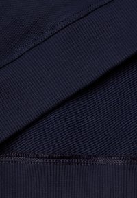 Navyblauwe stof met gestructureerde en gladde oppervlakken, met ribbel- en vlakgebreide secties, die een schoon, uniform ontwerp laat zien.