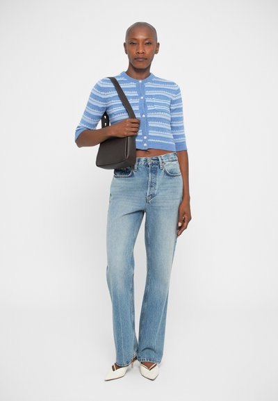 Afskåret blå strikket cardigan med hvide striber, knaplukning; parret med lyseblå lige ben jeans og hvide spidse hæle.