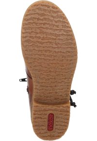 Semelle de botte en cuir marron avec un motif texturé en zigzag. Présente un logo rouge et un bout rond. Design plat et flexible avec une finition naturelle.