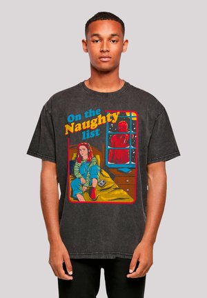 Black graphic t-shirt featuring a colorful illustration of a girl sitting on a bed with the text "On the Naughty List" in bold yellow and blue.