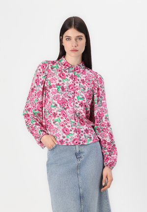Bloes met bloemenprint in roze, groen en grijs, met een knoopsluiting aan de voorkant, kraag en lange mouwen, gecombineerd met een spijkerrok.